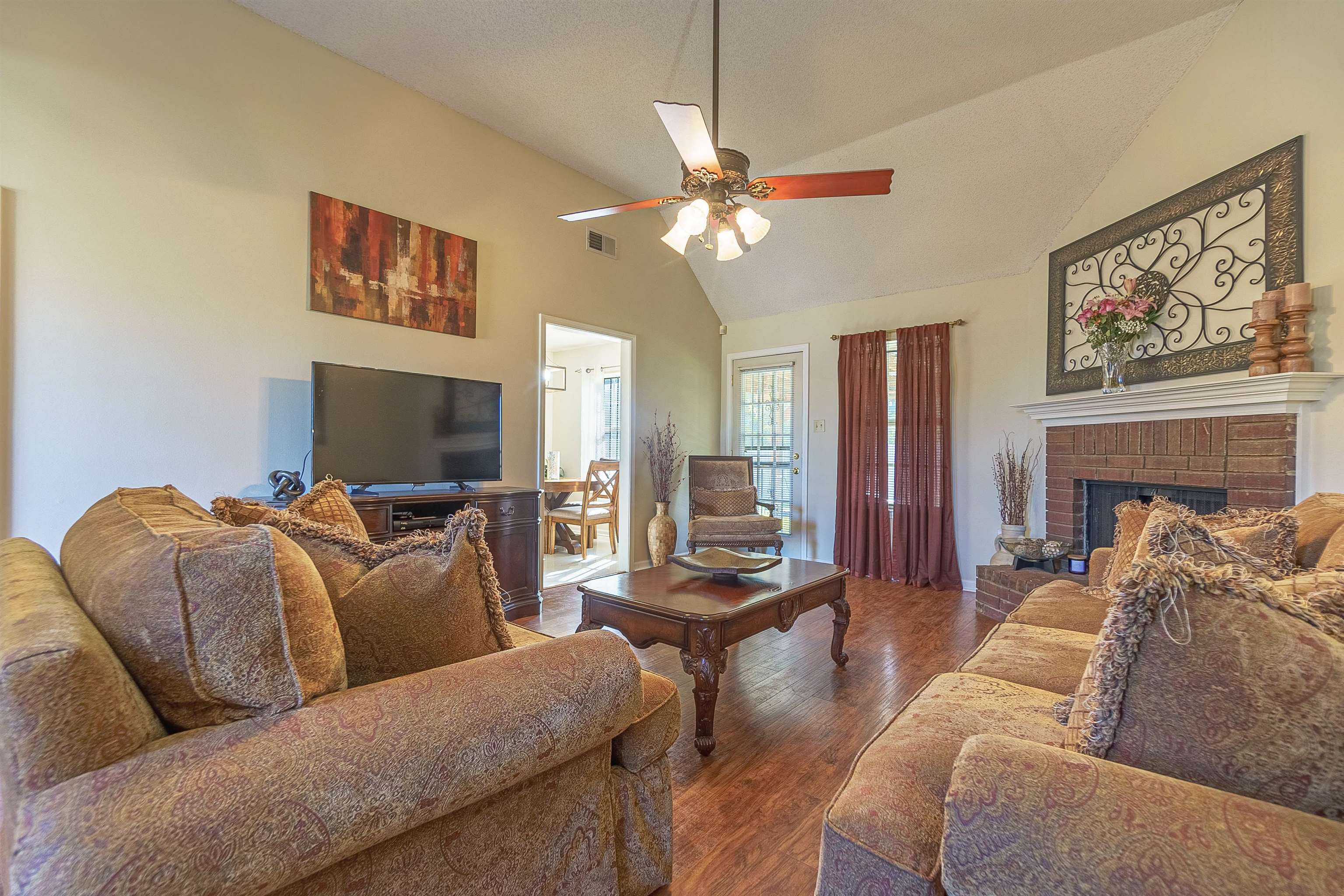 6419 Ragan Farm Drive Memphis, TN 38141 - Photo 7 of 27 Living room featuring ceiling fan, high vaulted ceiling, dark hardwood / wood-style floors, and a brick fireplace