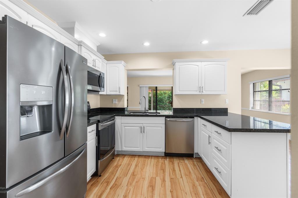 7836 Cloverfield Circle Boca Raton, FL 33433 - Photo 6 of 39 a kitchen with granite countertop stainless steel appliances a sink cabinets and a refrigerator