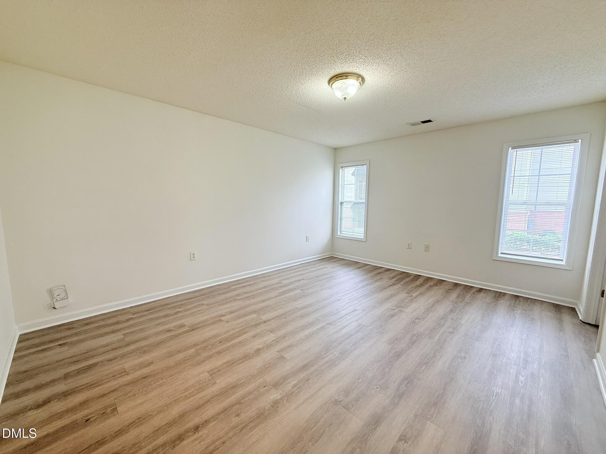 11381 Involute Place, Unit 103 Raleigh, NC 27617 - Photo 12 of 25 an empty room with wooden floor and windows