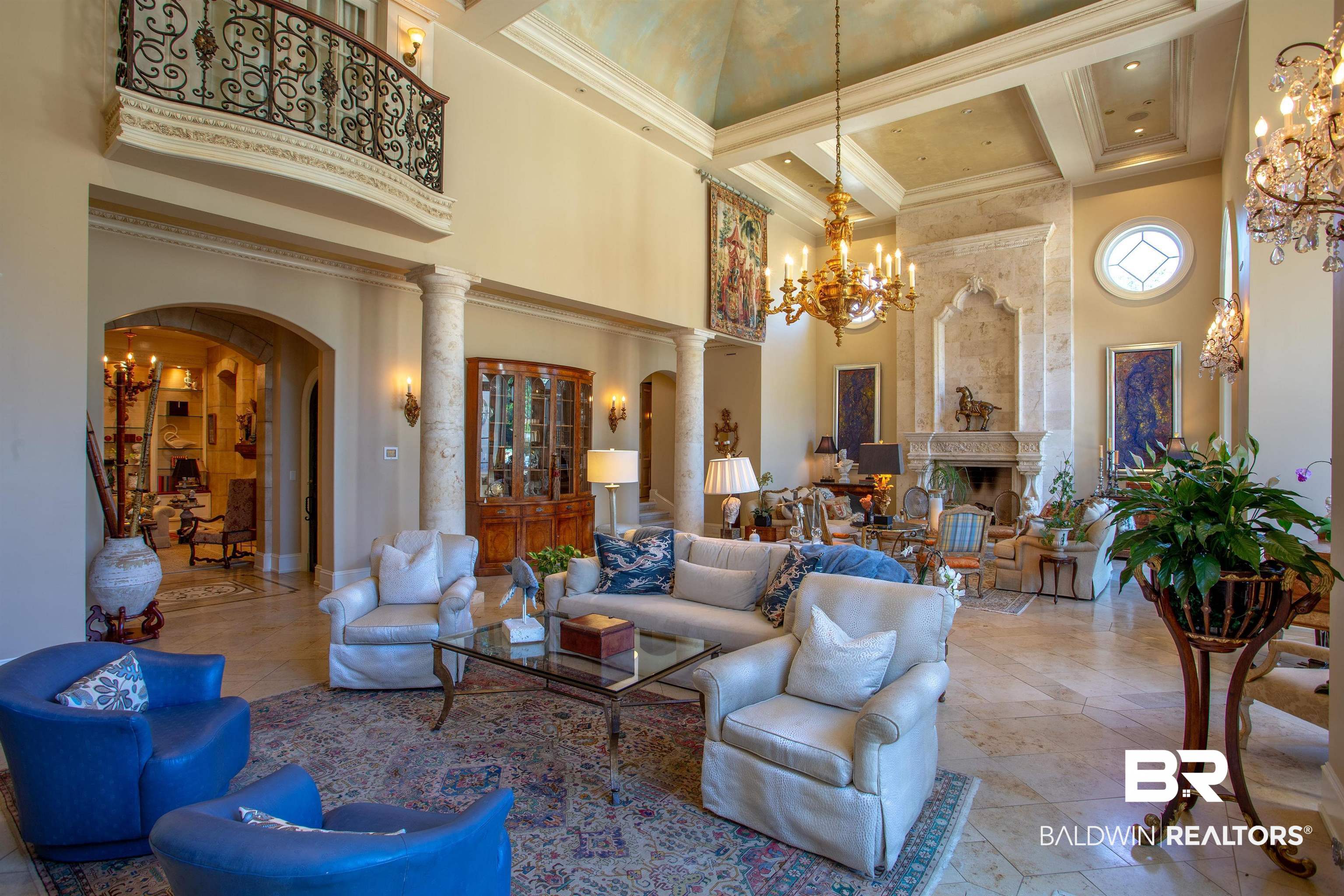 150 Austill Avenue Mobile, AL 36608 - Photo 10 of 39 Grand living space featuring a soaring ceiling, ornate fireplace with arched detailing, and a second-story balcony with decorative ironwork