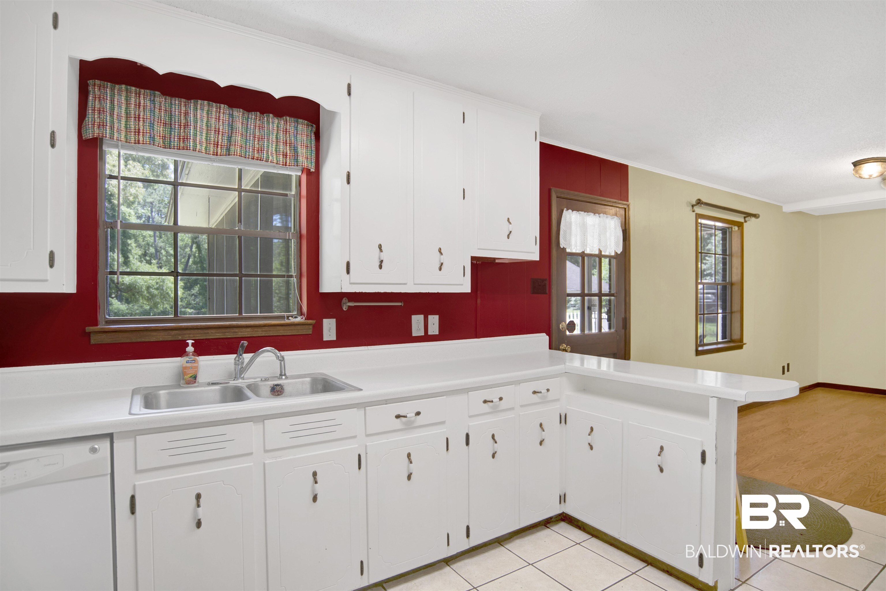 30888 Cemetery Road Daphne, AL 36527 - Photo 5 of 36 Kitchen featuring white cabinetry, a double basin stainless steel sink, a breakfast bar, and tile flooring