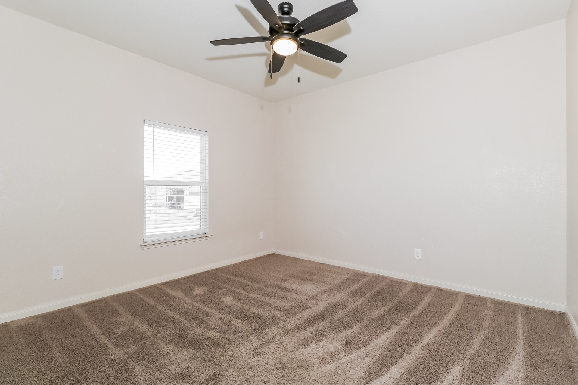 20017 Hubert R Humphrey Road Manor, TX 78653 - Photo 17 of 27 Well-lit room with plush carpeting and a modern ceiling fan, offering a comfortable living space.