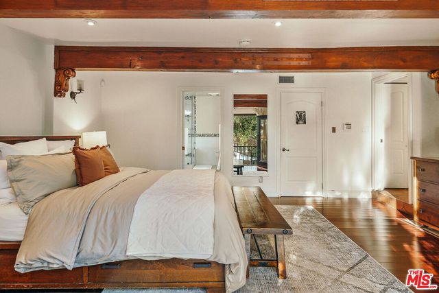 a view of a patio with table and chairs under an umbrella with large trees