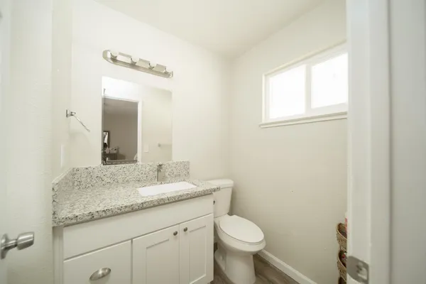 a bathroom with a granite countertop sink a toilet and a mirror