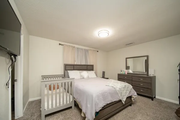 a bedroom with a bed and a flat tv screen on the dresser