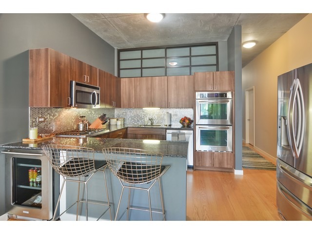 235 West Van Buren Street, Unit 1616 Chicago, IL 60607 - Photo 7 of 16 a kitchen with kitchen island granite countertop a stove a sink and a microwave