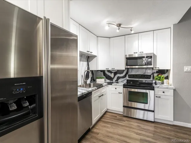 a kitchen with stainless steel appliances kitchen island granite countertop a stove a sink and a refrigerator