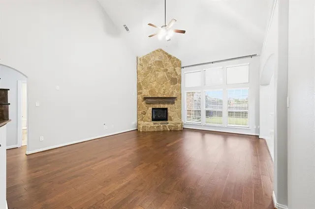 an empty room with wooden floor fan and windows