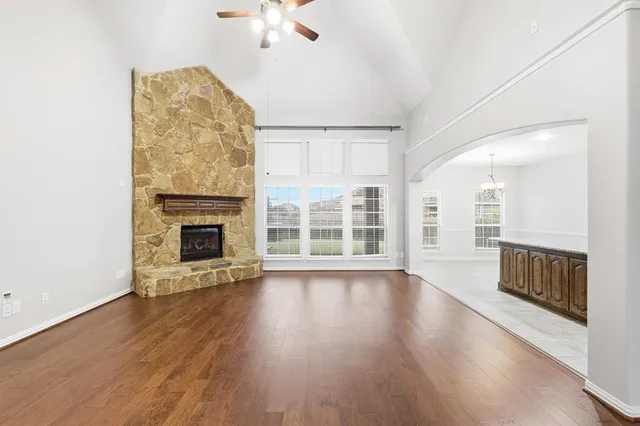 an empty room with wooden floor fireplace and windows