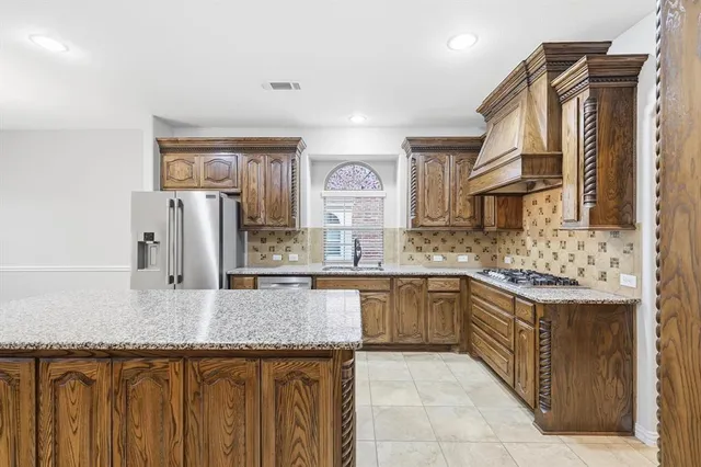 a kitchen with stainless steel appliances granite countertop a sink and dishwasher a refrigerator with wooden cabinets