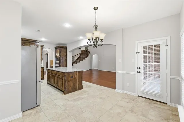 a living room with stainless steel appliances granite countertop furniture and a chandelier