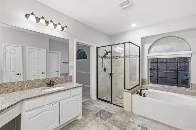 a spacious bathroom with a granite countertop tub mirror and double vanity