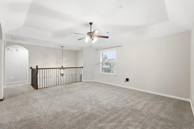 an empty room with staircase and a ceiling fan