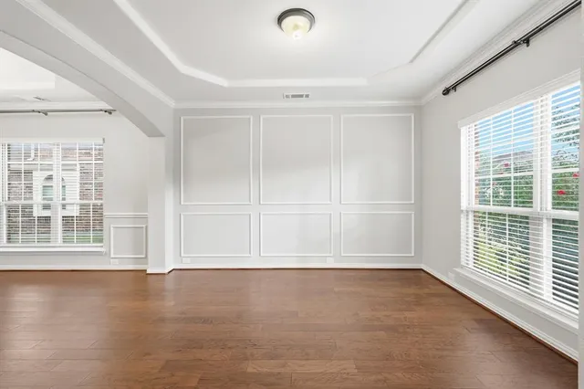 an empty room with wooden floor and windows with curtains