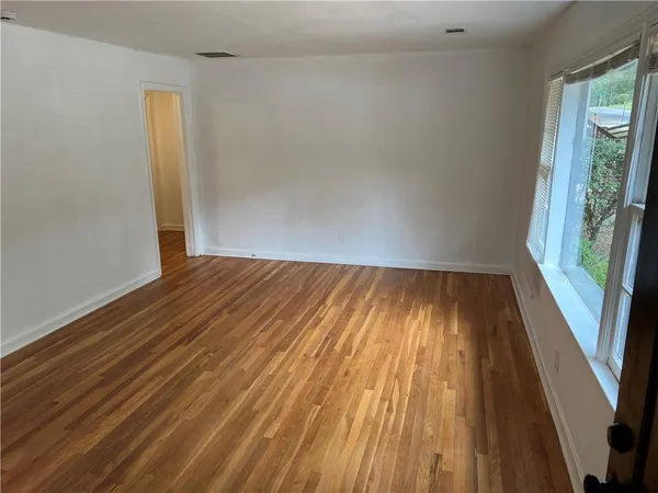 a view of an empty room with wooden floor and a window