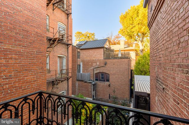 a view of a brick wall with a tree in front of it