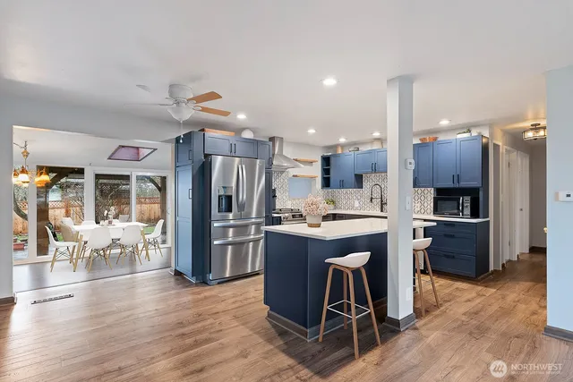 a kitchen with stainless steel appliances kitchen island granite countertop a table chairs stove and refrigerator