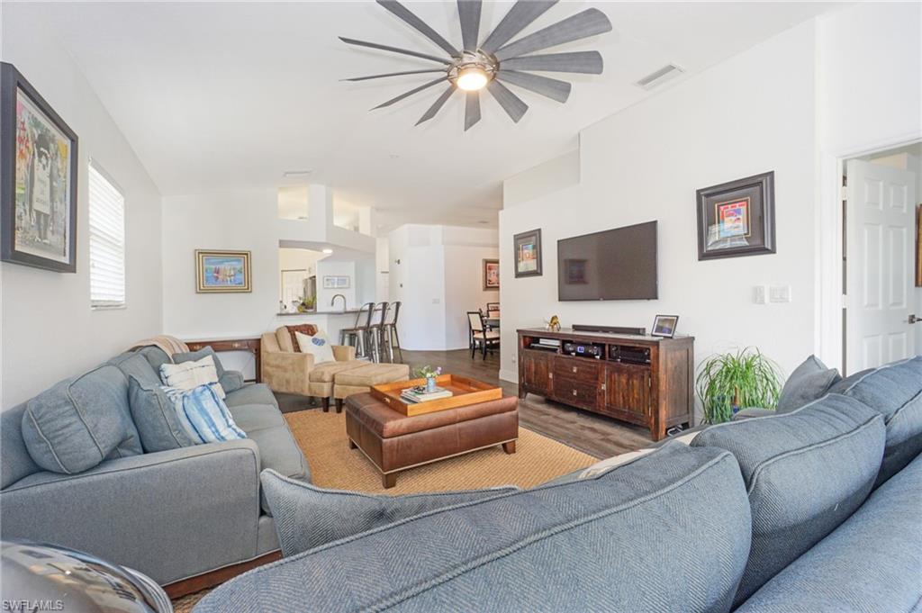 6910 Satinleaf Road North, Unit 204 Naples, FL 34109 - Photo 11 of 31 Living area featuring visible vents, wood finished floors, ceiling fan, and vaulted ceiling