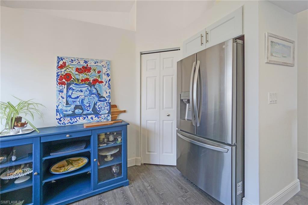 6910 Satinleaf Road North, Unit 204 Naples, FL 34109 - Photo 15 of 31 Kitchen featuring baseboards, dark wood-style flooring, white cabinets, and stainless steel fridge