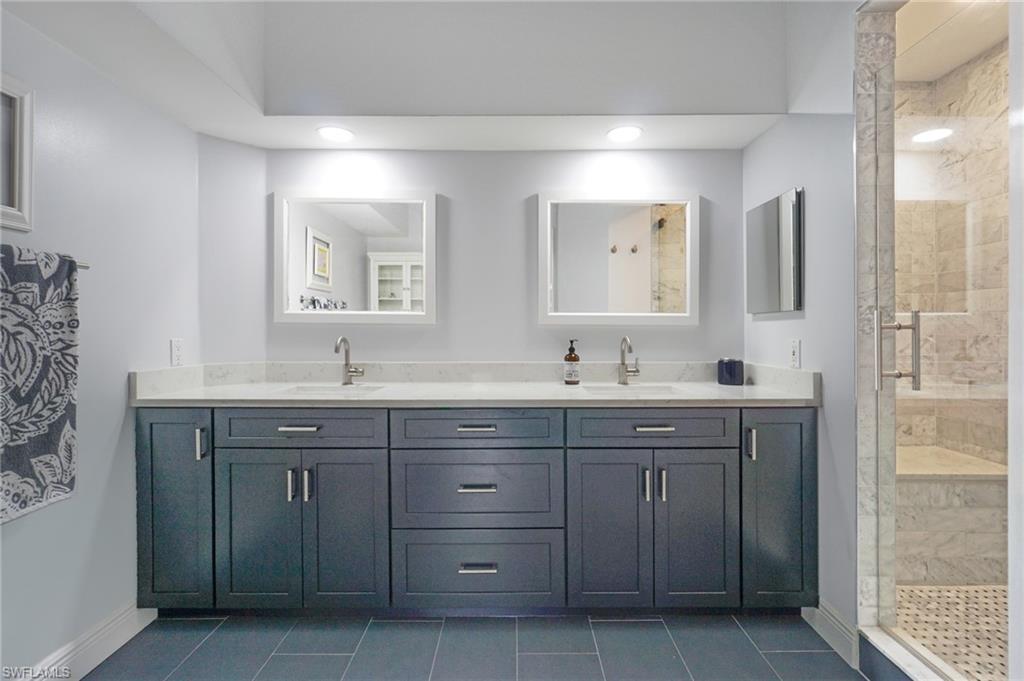 6910 Satinleaf Road North, Unit 204 Naples, FL 34109 - Photo 18 of 31 Bathroom with a shower stall, tile patterned floors, double vanity, and a sink