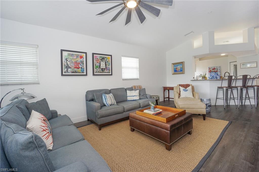 6910 Satinleaf Road North, Unit 204 Naples, FL 34109 - Photo 5 of 31 Living area with vaulted ceiling, a ceiling fan, wood finished floors, baseboards, and visible vents