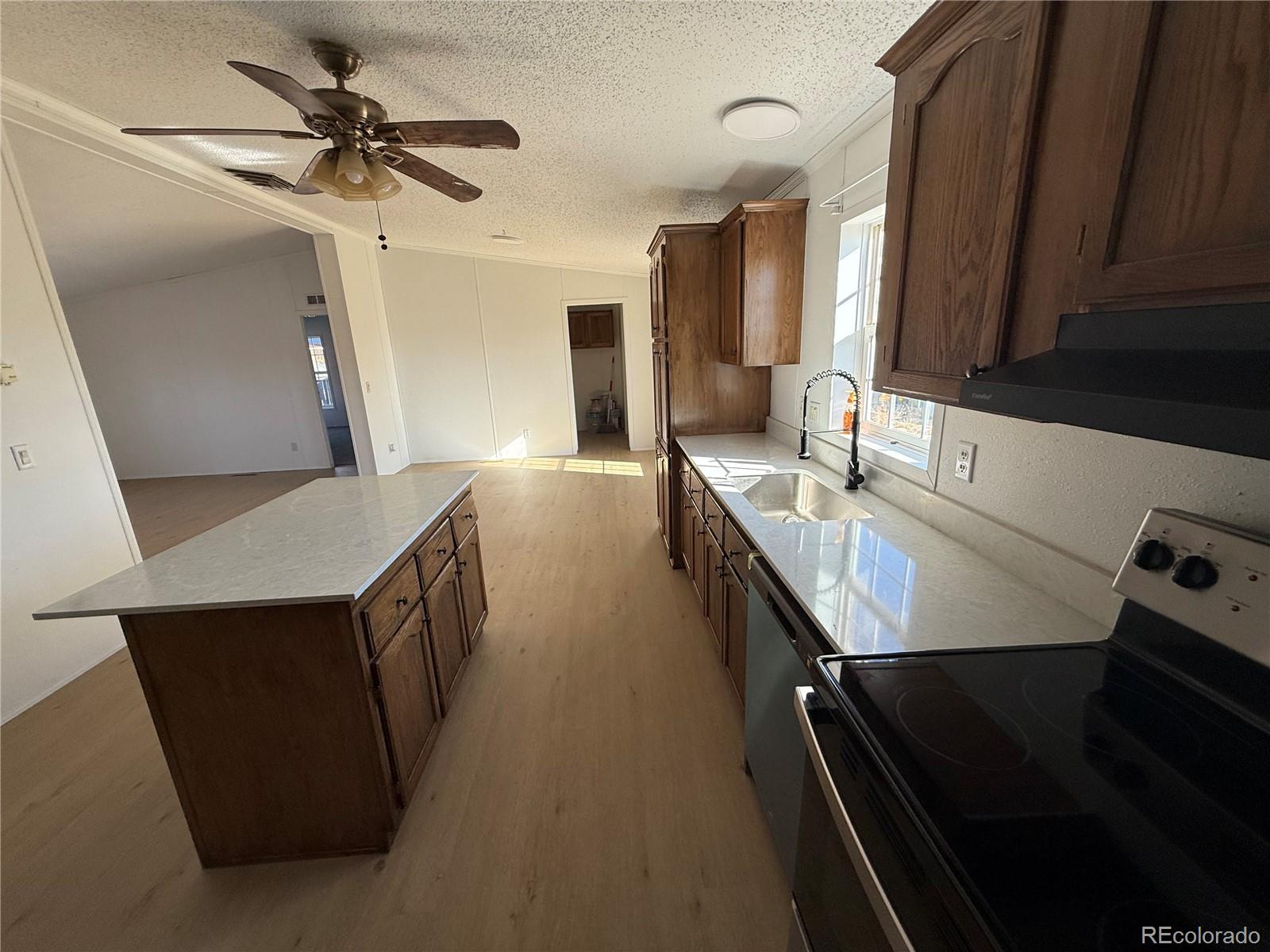 623 Prairie Avenue Brighton, CO 80603 - Photo 12 of 35 a kitchen with kitchen island a stove a sink and a refrigerator with wooden floor