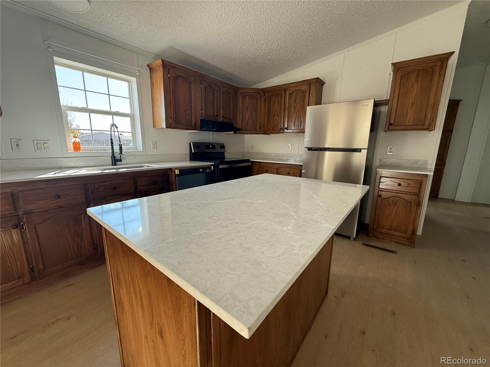 623 Prairie Avenue Brighton, CO 80603 - Photo 27 of 35 a kitchen with refrigerator cabinets and wooden floor