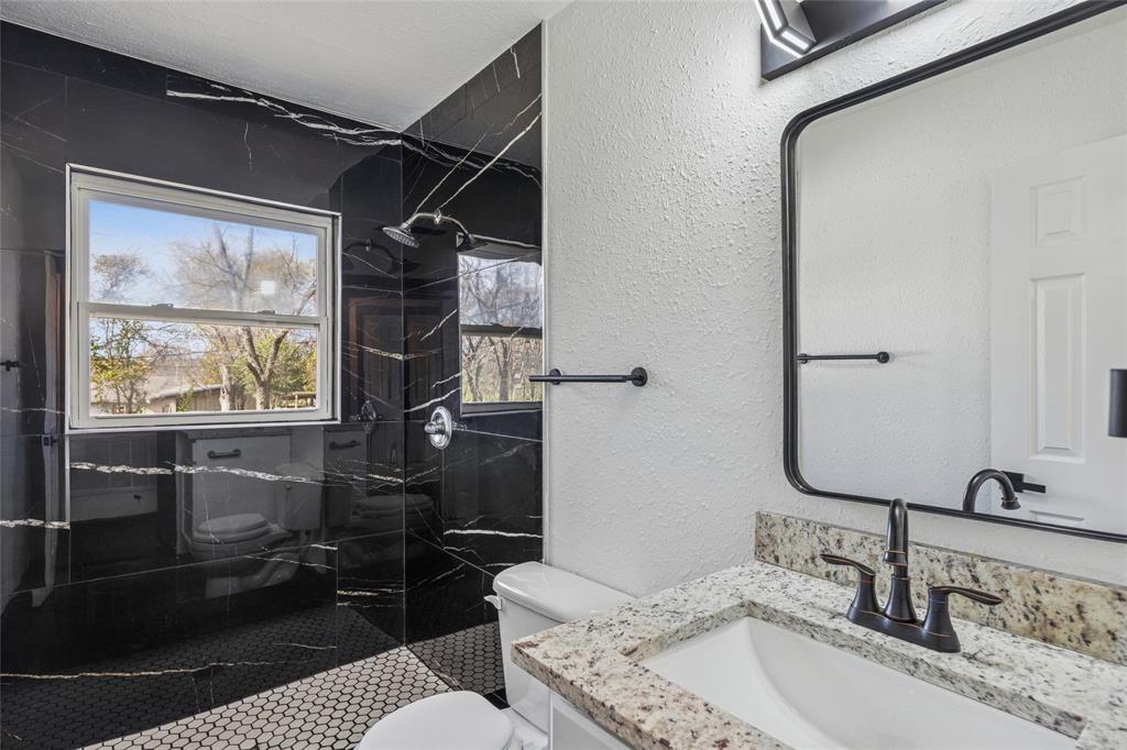 4816 Foard Street Fort Worth, TX 76119 - Photo 17 of 25 a bathroom with a granite countertop sink a mirror and shower