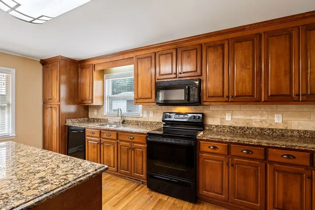 a kitchen with stainless steel appliances granite countertop wooden cabinets and a stove top oven