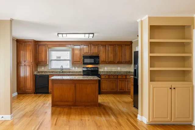 a kitchen with stainless steel appliances granite countertop a stove a sink and a refrigerator with wooden floors