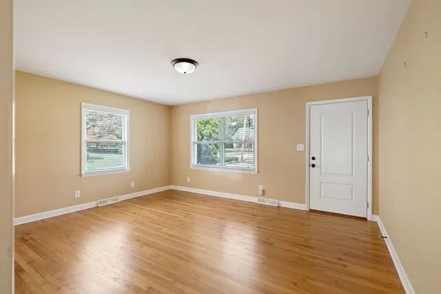 a view of an empty room with wooden floor and a window