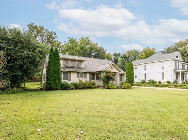 a view of a house with a big yard and large trees