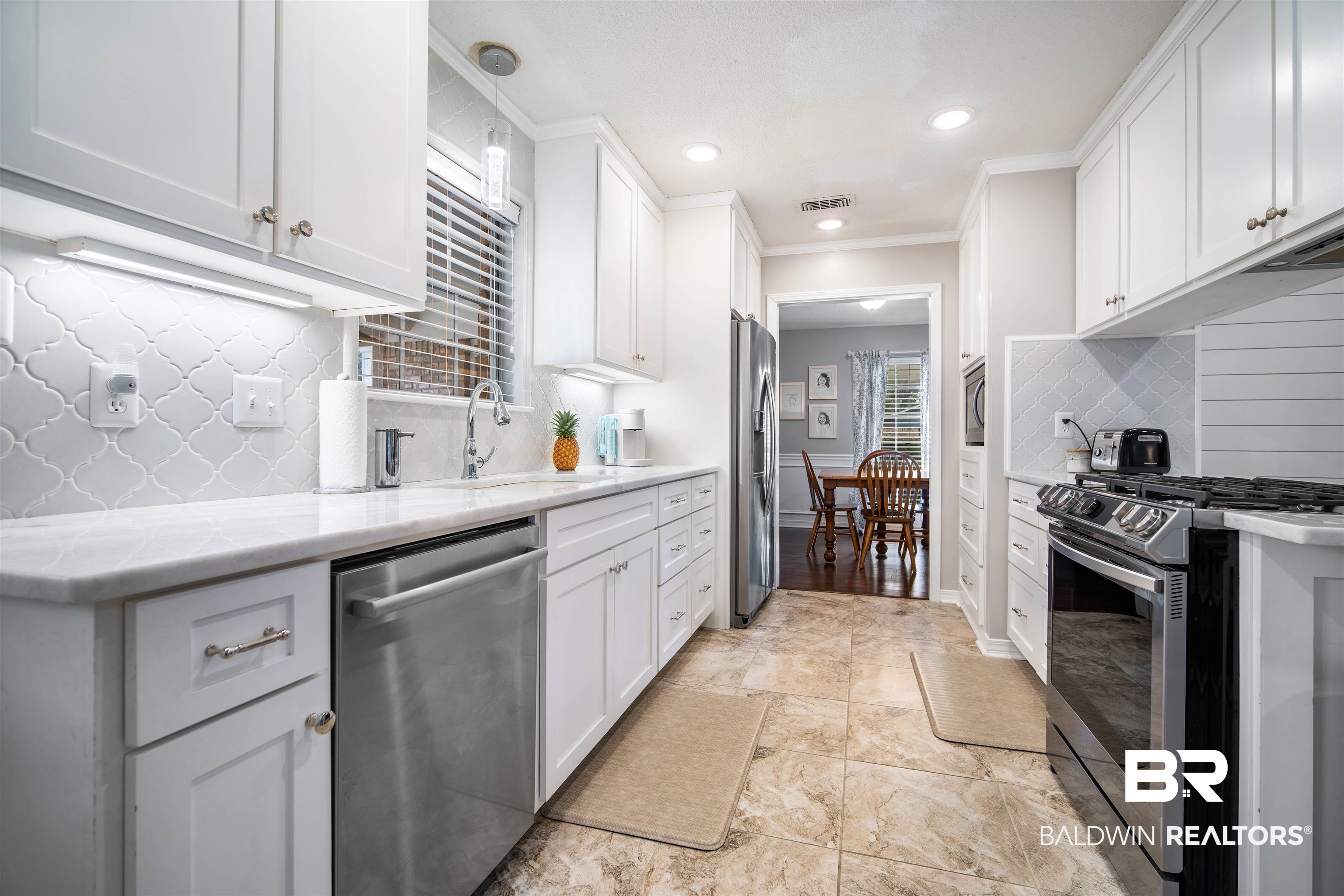 4228 Spring Valley Drive South Mobile, AL 36693 - Photo 10 of 31 Kitchen featuring white cabinetry, sink, tasteful backsplash, crown molding, and appliances with stainless steel finishes
