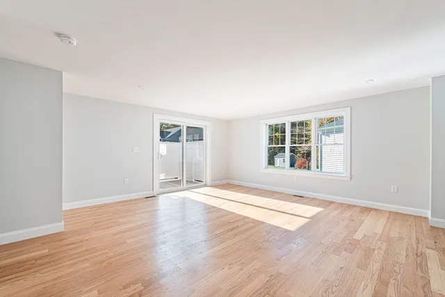 a view of an empty room with wooden floor and windows