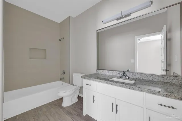 a bathroom with a granite countertop sink a toilet and bathtub