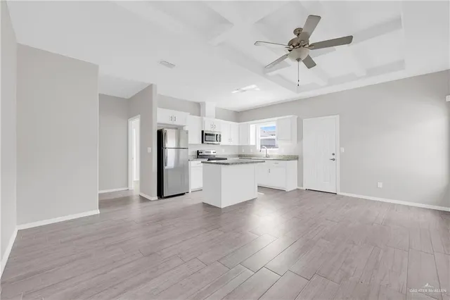 a view of kitchen with stainless steel appliances refrigerator stove and wooden floor