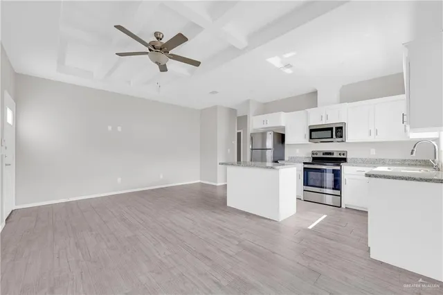 a kitchen with stainless steel appliances white cabinets and wooden floor