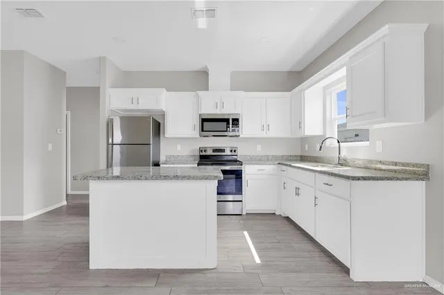 a kitchen with granite countertop a sink stove top oven and refrigerator