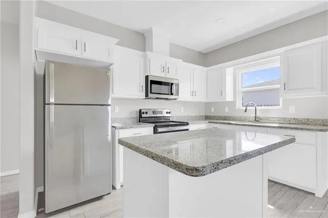 a kitchen with granite countertop stainless steel appliances a refrigerator a sink a stove a microwave and cabinets