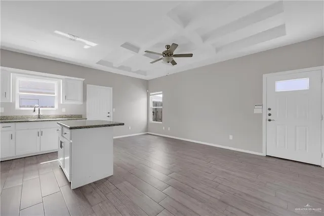 a kitchen with granite countertop white cabinets a sink a window and stainless steel appliances