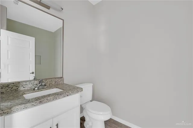 a bathroom with a granite countertop sink and a toilet