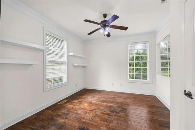 a view of a livingroom with a fireplace a ceiling fan and windows