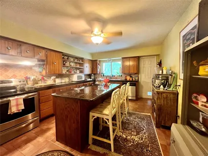 a kitchen with stainless steel appliances granite countertop a stove a sink dishwasher and a refrigerator with wooden floor