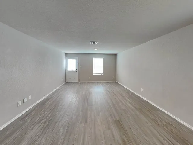 a view of empty room with window and wooden floor