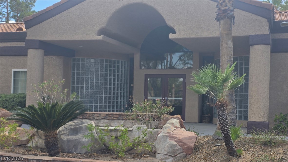 9325 West Desert Inn Road, Unit 123 Las Vegas, NV 89117 - Photo 34 of 36 A terracotta-tiled roof crowns this stucco-finished entrance, framed by mature desert landscaping.