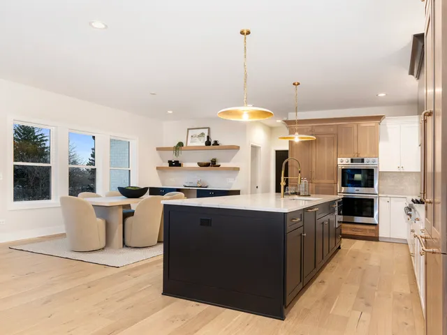 a kitchen with stainless steel appliances a stove a sink a refrigerator a dining table and chairs