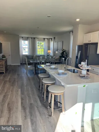 a kitchen with a sink dishwasher a dining table and chairs with wooden floor