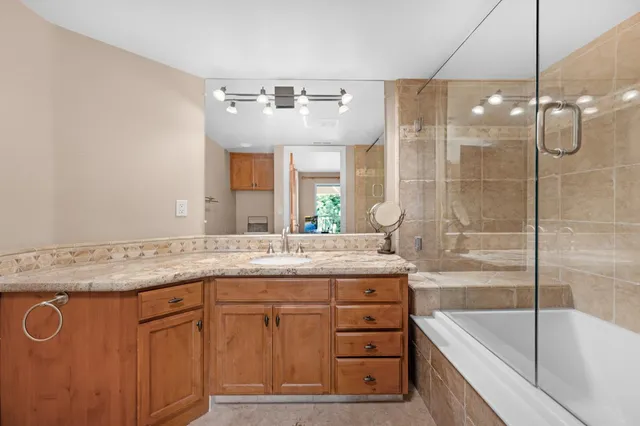 a bathroom with a granite countertop sink a large mirror and a bathtub