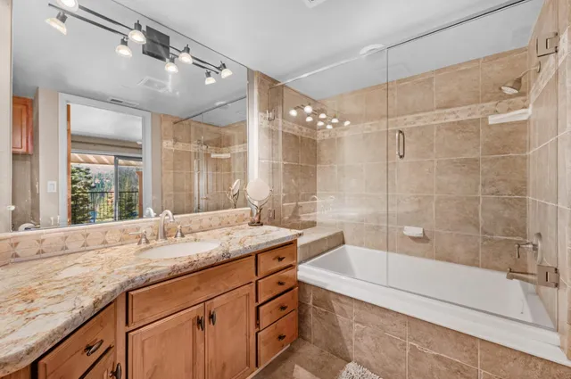 a bathroom with a granite countertop sink a large mirror and a bathtub