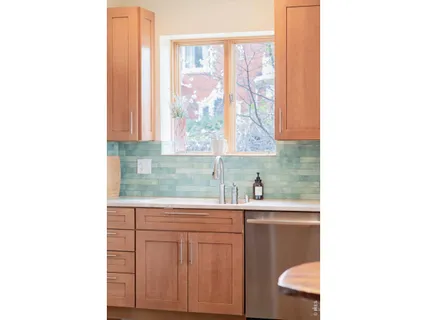 a kitchen with a stove a sink and white cabinets with wooden floors